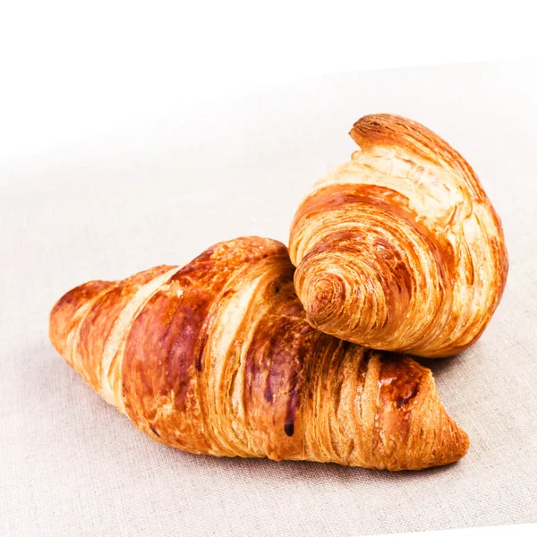 Färska croissanter på linne duk på ett bord, närbild. — Stockfoto