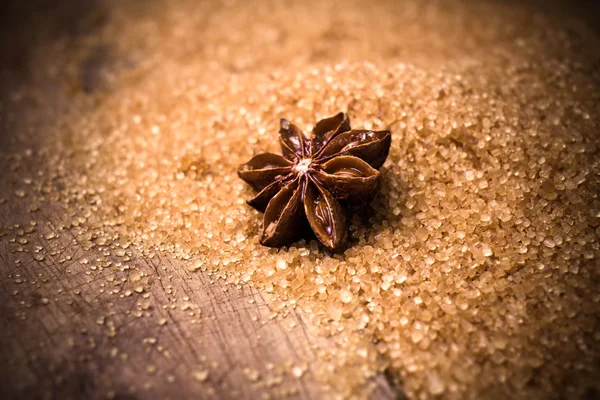 Anise star on brown cane sugar on wooden background — Stock Photo, Image