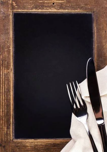 Vintage blackboard with wooden frame with linen towel and serving cutlery — Stock Photo, Image