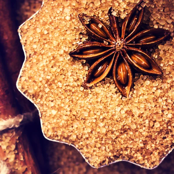 Cinnamon sticks, nuts and star anise on brown sugar, macro. — Stock Photo, Image