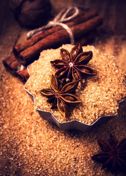 Tyčinky skořice, ořechy a badyánu na hnědý cukr, makro. — Stock fotografie
