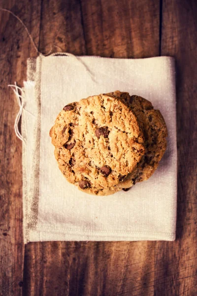 Stacked chocolate chip cookies on white linen napkin