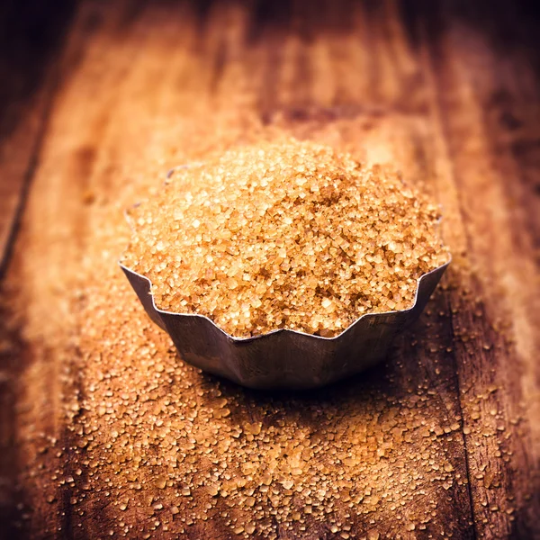 Haufen brauner Zucker in Stahlschale, verwitterter Holztischhintergrund — Stockfoto