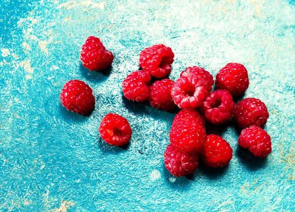 Haldy zralé maliny na modré barevné pozadí makro. — Stock fotografie