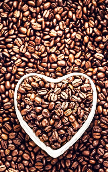 Grains de café torréfiés dans un bol en forme de coeur — Photo