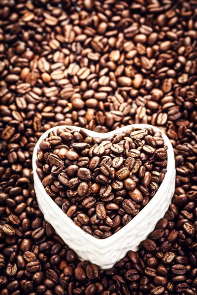 Grains de café torréfiés dans un bol en forme de coeur — Photo