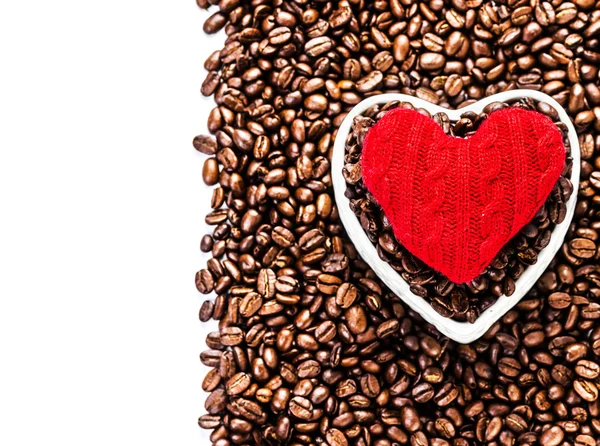 Grains de café torréfiés avec coeur rouge sur fond de grains de café — Photo