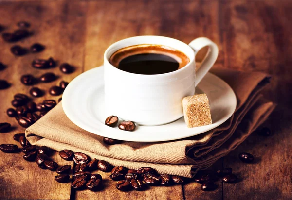 Xícara de café com grãos de café na mesa de madeira — Fotografia de Stock