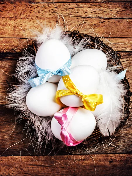 Nido de Pascua con huevos, cintas y plumas blancas — Foto de Stock