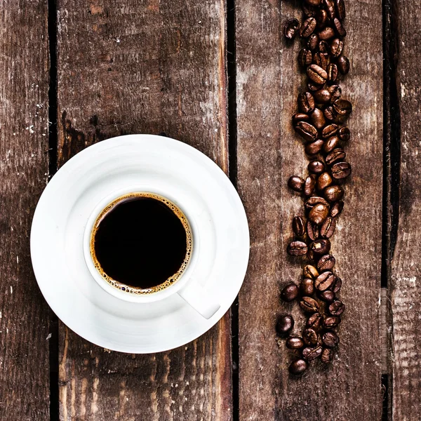 Taza de café negro y granos de café tostados — Foto de Stock