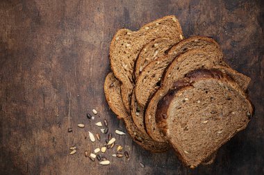 Koyu ahşap arka planda dilimlenmiş kepekli ekmeğin üst görüntüsü. Tohumlu ve kırıntılı taze ekşi ekmek..