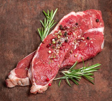 Fresh beef steak meat on old wooden table. Raw meat with spices, salt and rosemary herb. Copyspace. Top vie