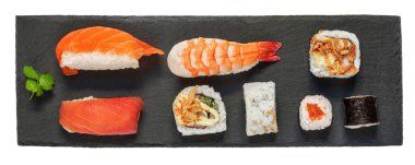 Sushi rolls set an a black slate  desk isolated on a white background. Sushi with salmon, shrimps,  tuna and avocado. Top view. Flat la
