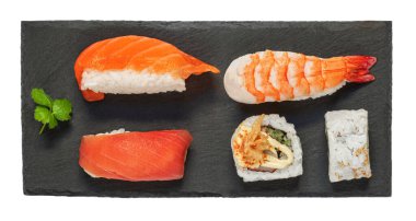 Sushi rolls set an a black slate  desk isolated on a white background. Sushi with salmon, shrimps,  tuna and avocado. Top view. Flat la