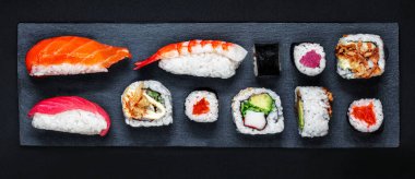 Sushi set on a black slate  background. Japan restaurant menu. Sushi with salmon, tuna and avocado. Top view. 