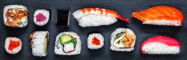 Sushi set on a black slate  background. Japan restaurant menu. Sushi with salmon, tuna and avocado. Top view. 