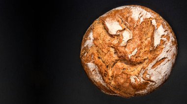 Top view of ructic wholegrain bread on a black slate background closeup. Top vie