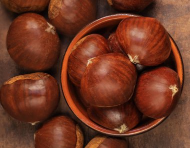 Chestnuts in a bowl  on a wooden background. Autumn fall seasonal composition with horse chestnuts