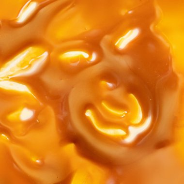 Liquid sweet melted caramel splash as a background. Toffee caramel sauce or maple syrup swirl pattern top view. Flat lay