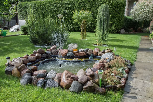 Fontana in un bellissimo giardino con piante — Foto Stock