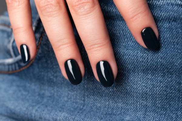 Hand med mörka svarta naglar på jeans — Stockfoto