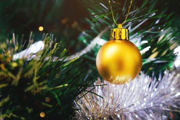 Zlatý míč na vánočním stromečku s rozmazanými světly bokeh — Stock fotografie