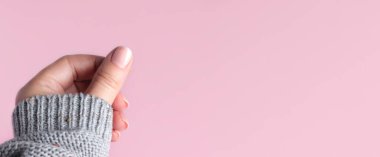 Pembe arka planda çıplak tırnaklı süveter.