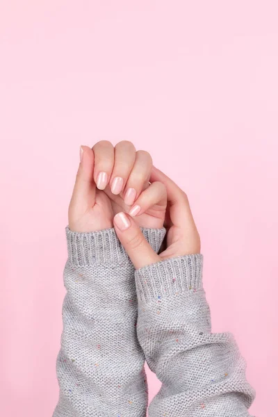 Handen in trui met naakte nagels op roze achtergrond — Stockfoto