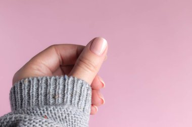 Pembe arka planda çıplak tırnaklı süveter.