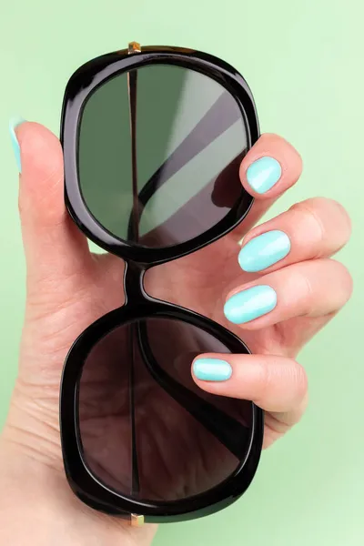 Γυναικείο Χέρι Όμορφο Μανικιούρ Μπλε Νύχια Μέντας Γυαλιά Ηλίου Πράσινο — Φωτογραφία Αρχείου