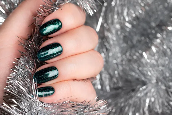 Hand met groene glitternagels met zilverkleurig tinsel — Stockfoto