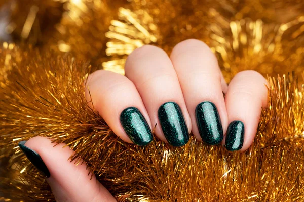 Hand met groene glitternagels met gouden tinsel — Stockfoto