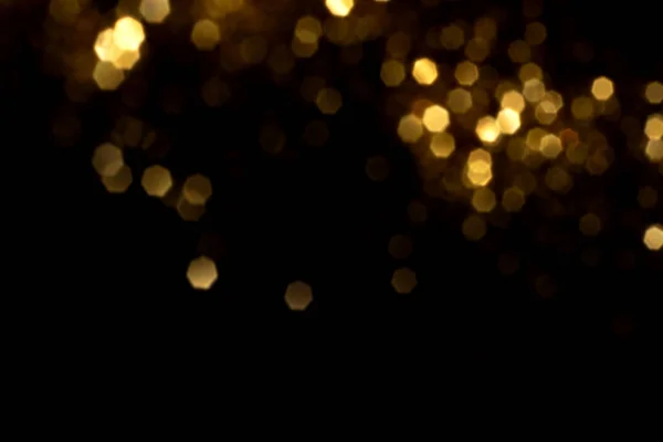 Luzes bokeh embaçadas douradas no fundo preto — Fotografia de Stock