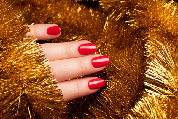 Рука с красными ногтями с золотой мишурой — стоковое фото