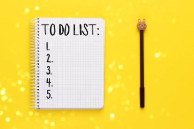 Liste yapılacak defter ve sarı arkaplanda bulanık ışıklı kalem bokeh