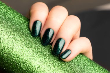 Parlak yeşil tırnaklı bir el.