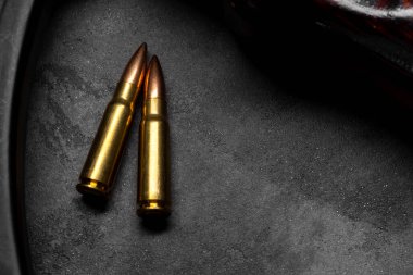 Gri beton arka planda iki kurşun ve Kalaşnikof saldırı tüfeği. Fişek 7.62 kalibre, AK 47 yakın çekim için.