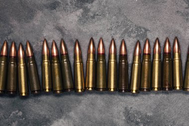 Gri arka plandaki kurşunlar. Kalaşnikof saldırı tüfeği için 7.62 kalibrelik fişekler. Üst manzara, düz uzanma