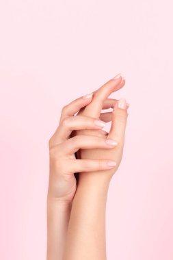 Güzel doğal manikürlü kadın elleri pembe arka planda pembe çıplak tırnaklar. Çivi bakımı kavramı