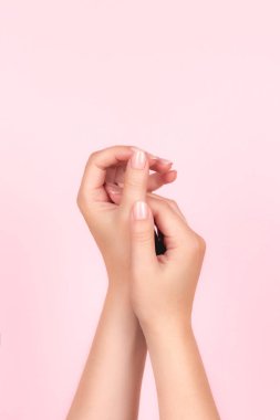 Güzel doğal manikürlü kadın elleri pembe arka planda pembe çıplak tırnaklar. Çivi bakımı kavramı