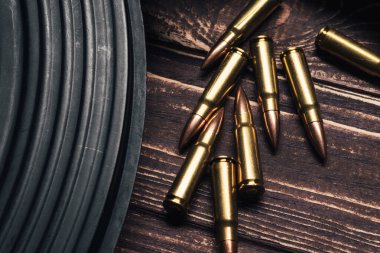 Mermiler ve Kalaşnikof saldırı tüfeği tahta arka planda. 47 kalibrelik yakın çekim için 7.62 kalibrelik fişekler. Seçici odak