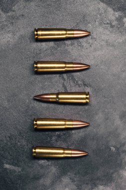 Gri arka plandaki kurşunlar. Diğerlerinden farklı istikamette konumlanmış bir mermi. Kalaşnikof saldırı tüfeği için 7.62 kalibrelik fişekler. Üst manzara, düz uzanma