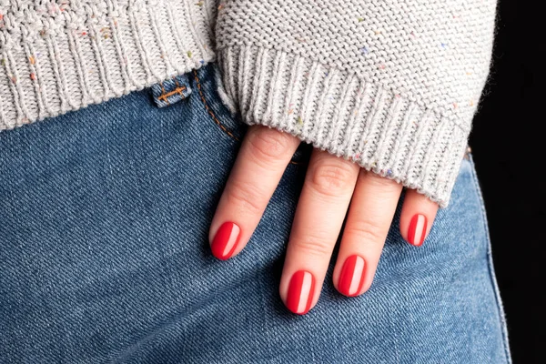 Güzel manikürlü bir kadın eli. Kotun üzerindeki kırmızı tırnaklar, yakın plan parmaklar. Seçici odak