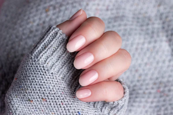身穿灰色针织毛衣 有着漂亮的自然修指甲的雌性手 粉色的裸体指甲 指甲护理概念 — 图库照片