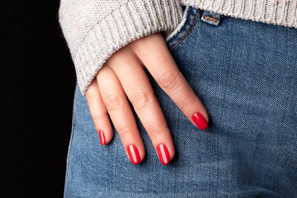 Güzel manikürlü bir kadın eli. Kotun üzerindeki kırmızı tırnaklar, yakın plan parmaklar.