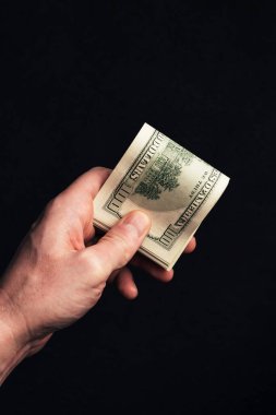 Siyah arka planda bize 100 dolarlık banknotlar tutan bir erkek. Amerikan paralı adam, yakın plan.