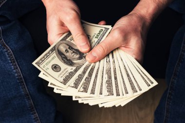 Erkek eller bize 100 dolarlık banknotlar tutuyor. Amerikan paralı adam, yakın plan.