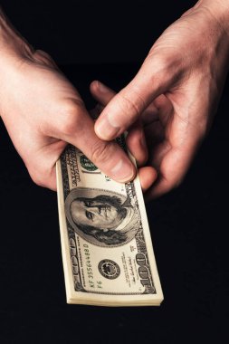 Erkek eller bize 100 dolarlık banknotlar tutuyor.