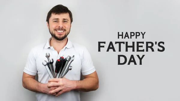 Smiling man with bouquet of wrenches and screwdrivers. Happy fathers day concept or greeting card