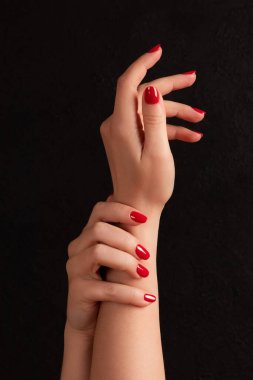Güzel manikürlü kadın elleri. Siyah arka planda kırmızı tırnaklar. Çivi, cilt bakımı konsepti